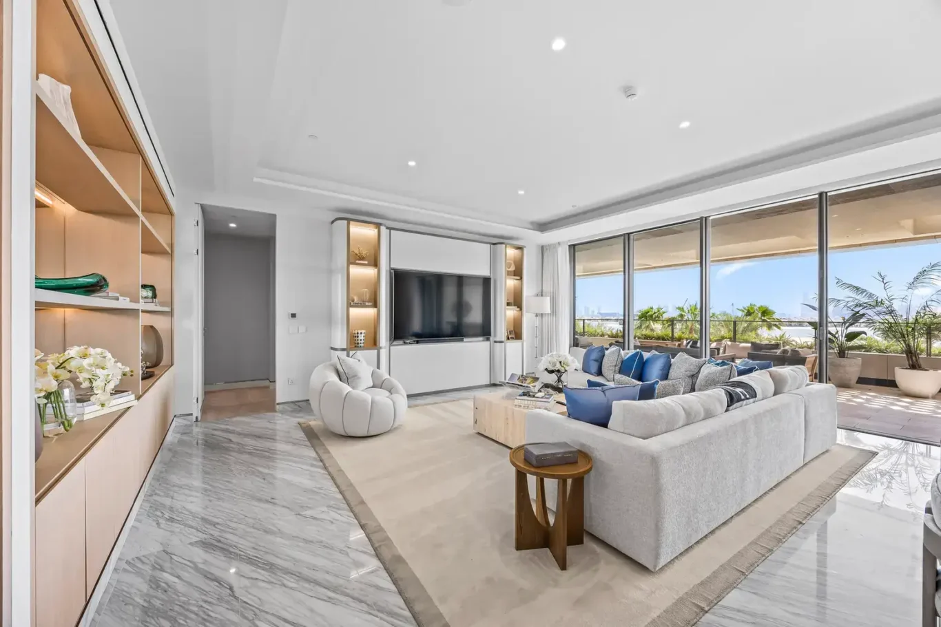 Living room with built-in shelving and marble floor in a furnished three-bedroom residence at Atlantis The Royal, Palm Jumeirah, photographed for Apex Homes Real Estate.