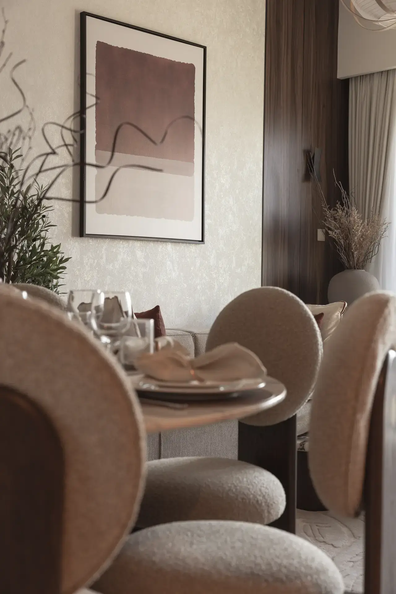 Dining area with round boucle chairs, set table and abstract art. Interior design photography for Aziza Home by MRPS in Dubai.