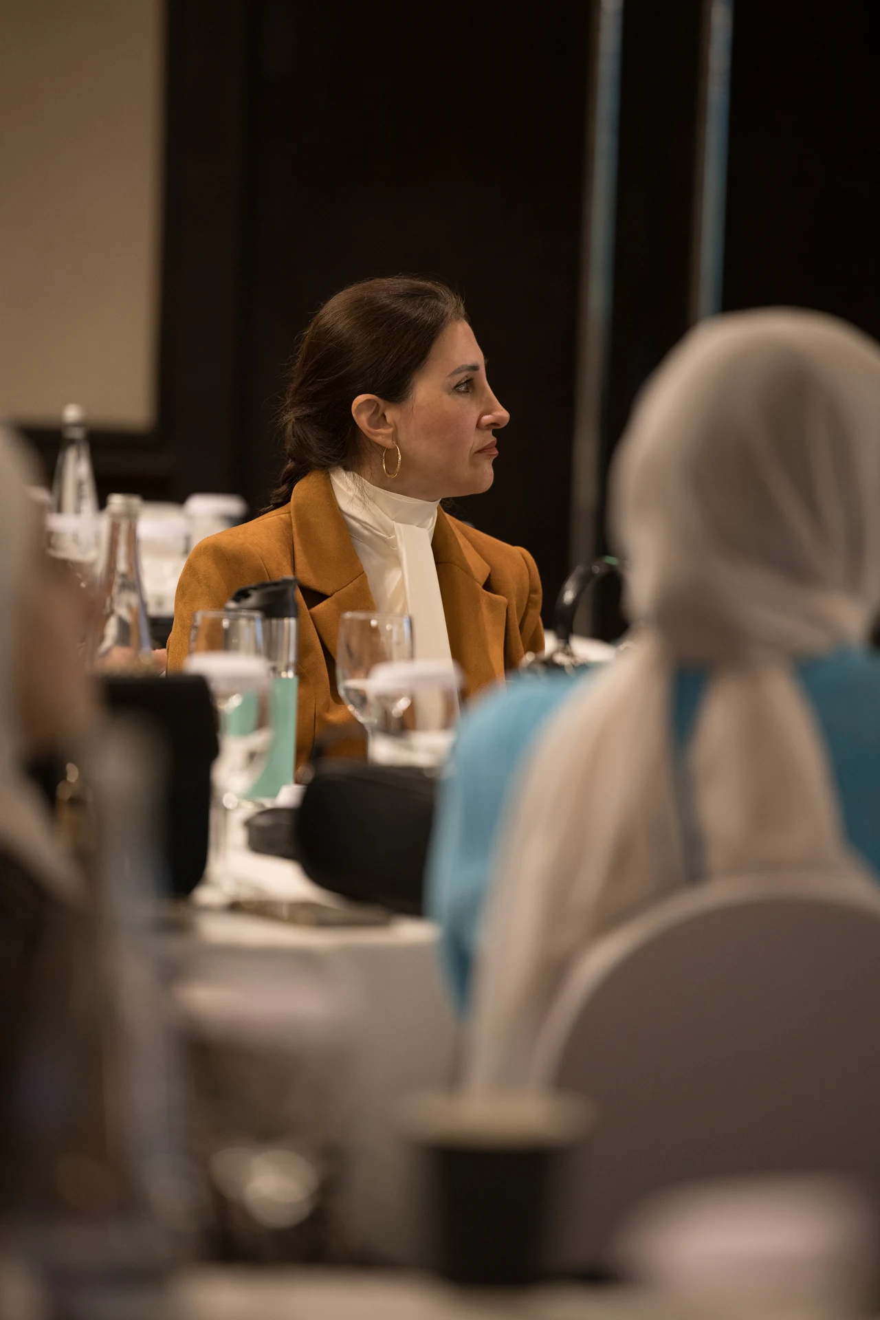 Guest at a table listening to a session with a glass of water in front of her. Corporate event photography by MRPS for My Arabic Publishing at Movenpick Grand Al Bustan, Dubai.