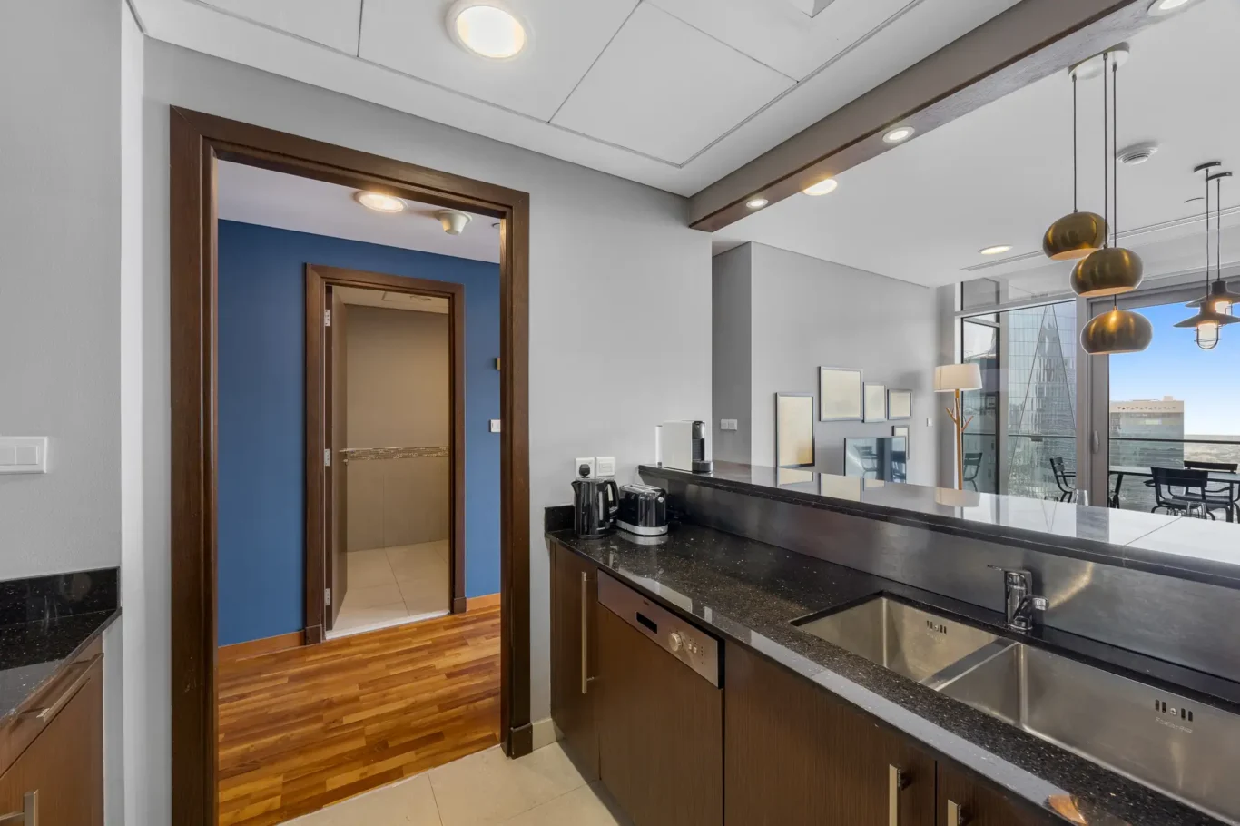 Kitchen with breakfast counter open to the living room in a Your Stay Apartments one-bedroom at Burj Daman, DIFC, Dubai.
