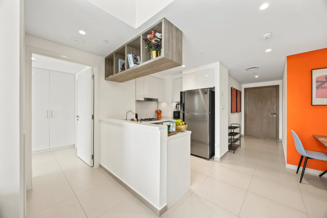 Open kitchen seen from the hallway with the living room beyond. Day, twilight and night Airbnb photography by MRPS for Vista Haus Holiday Homes in Downtown Dubai.