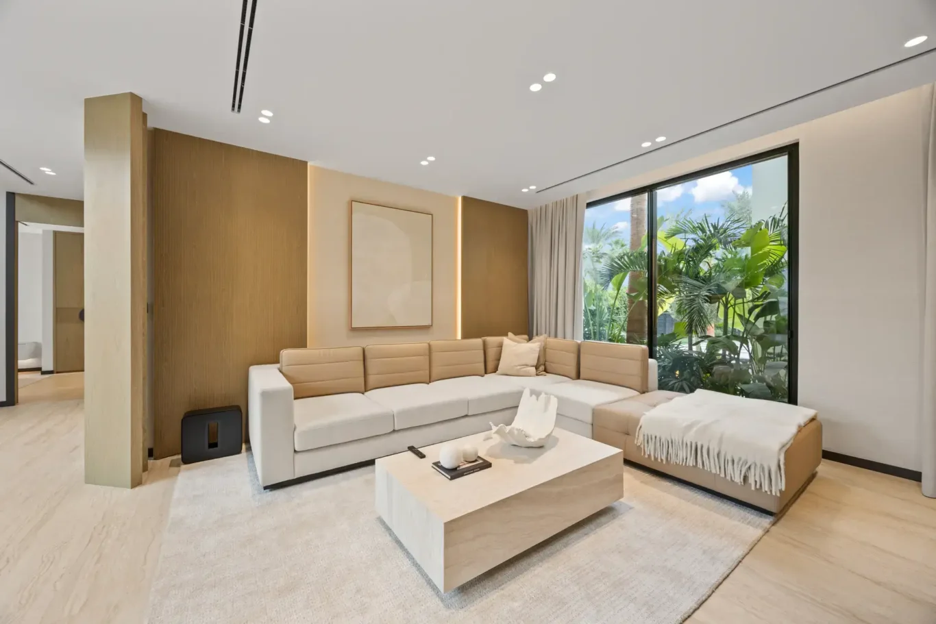 Family lounge with a sectional sofa and garden view, luxury villa in Jumeirah Islands, Dubai.
