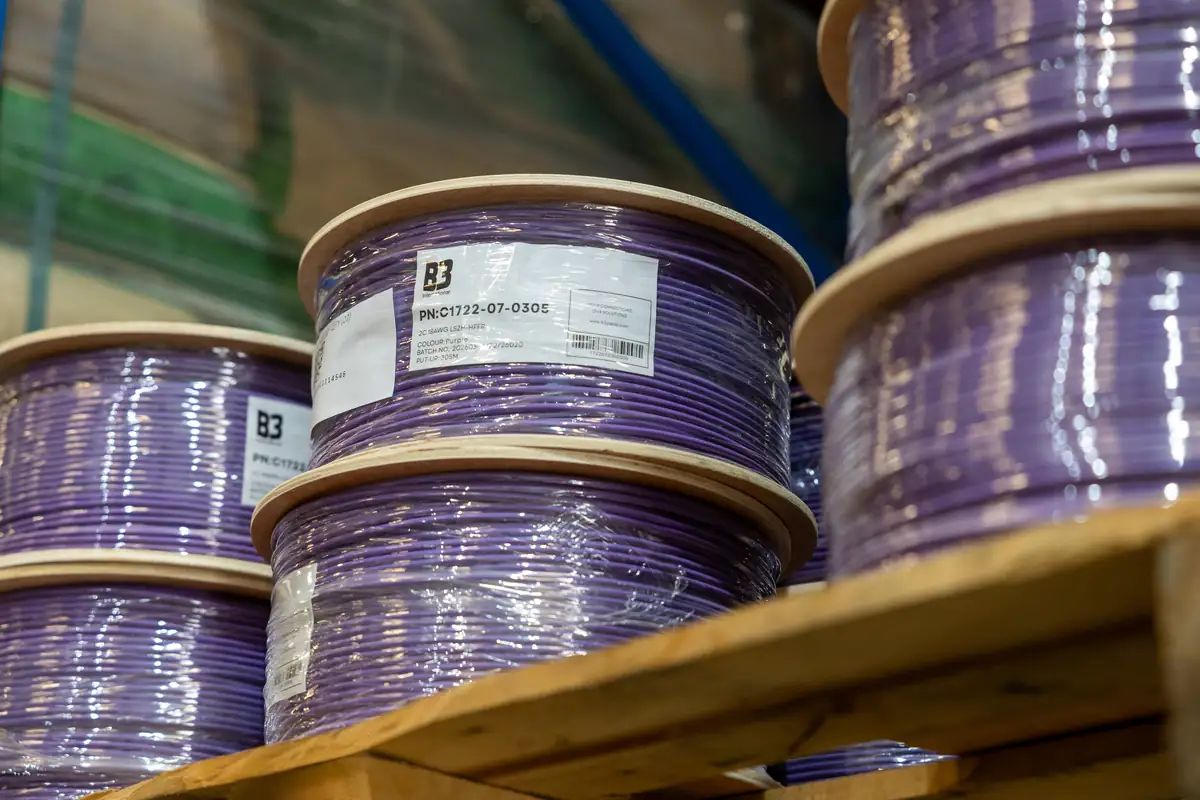 Close-up of purple B3 International cable reels with product labels on a warehouse shelf.