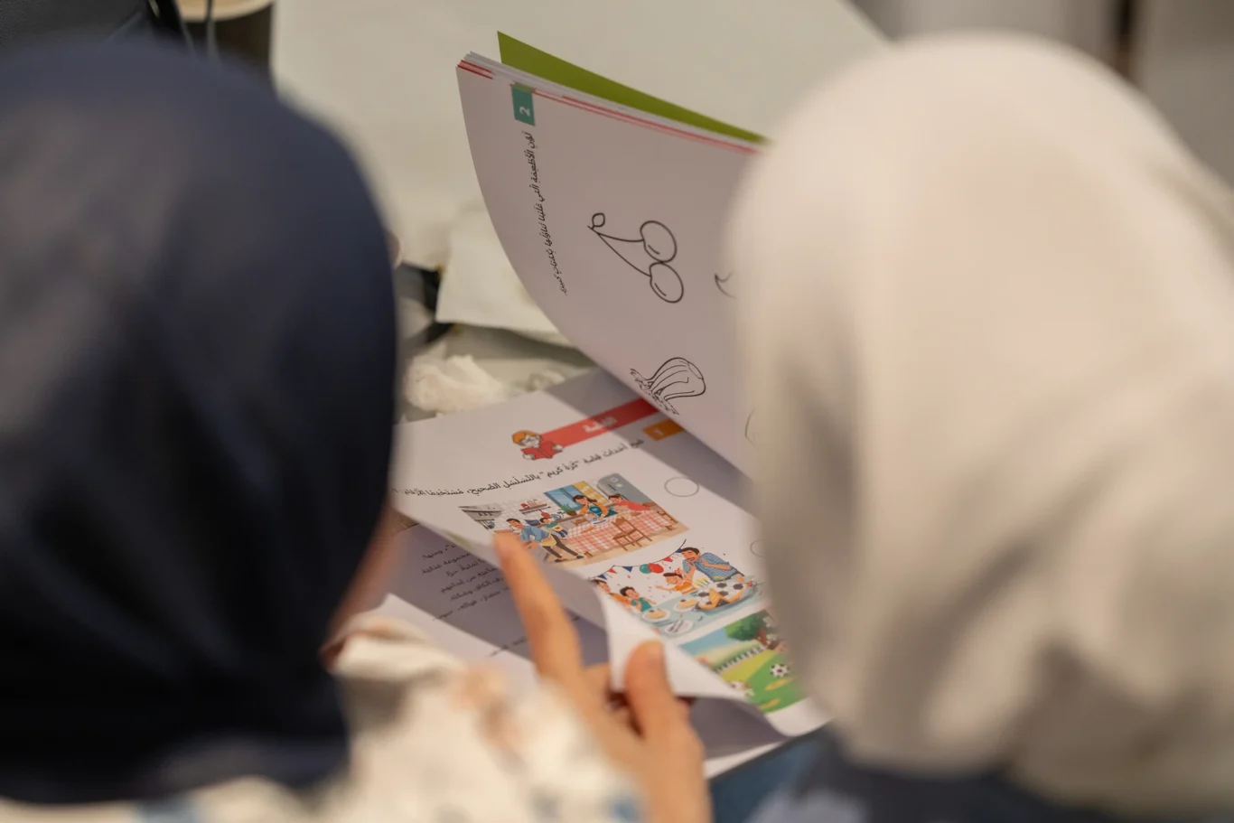 Guest leafing through an illustrated children's book during the break. Corporate event photography by MRPS for My Arabic Publishing at Movenpick Grand Al Bustan, Dubai.