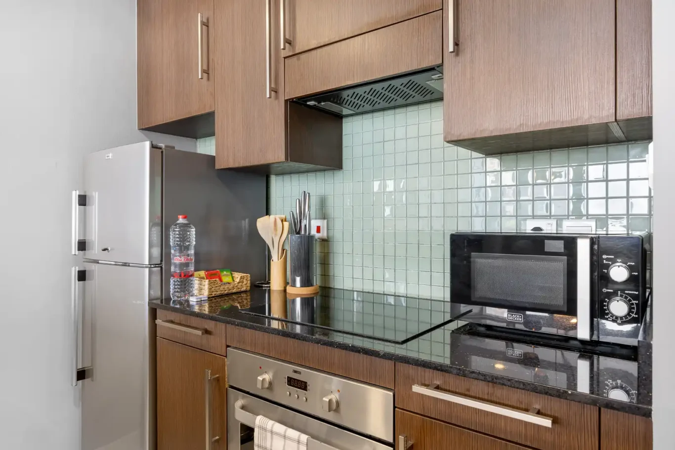 Kitchen with fridge, oven, microwave and kettle in a Your Stay Apartments one-bedroom at Burj Daman, DIFC, Dubai.