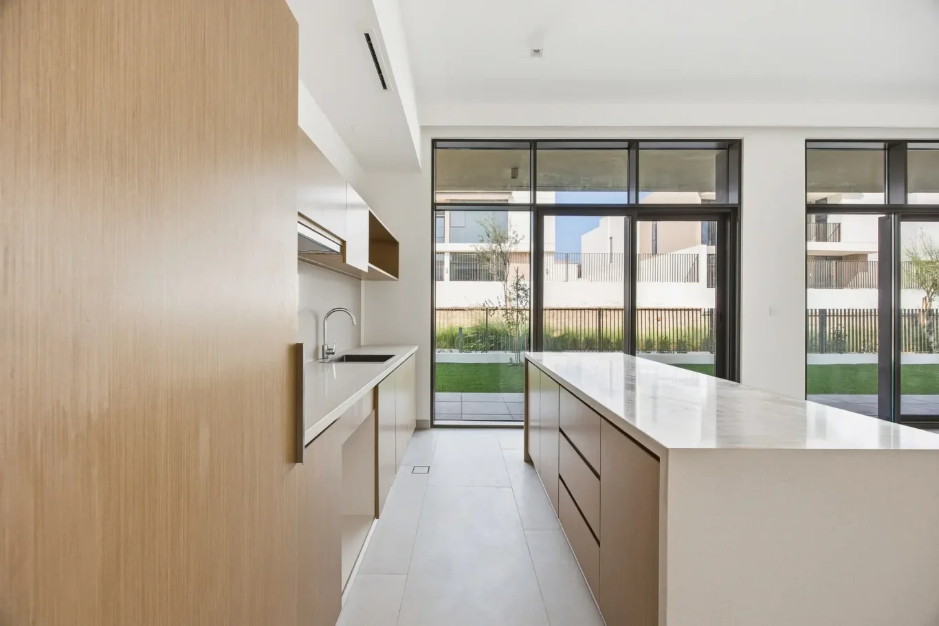 Kitchen island with sliding glass doors to the garden. Villa photography by MRPS in Dubai for ELITE Property Brokerage.