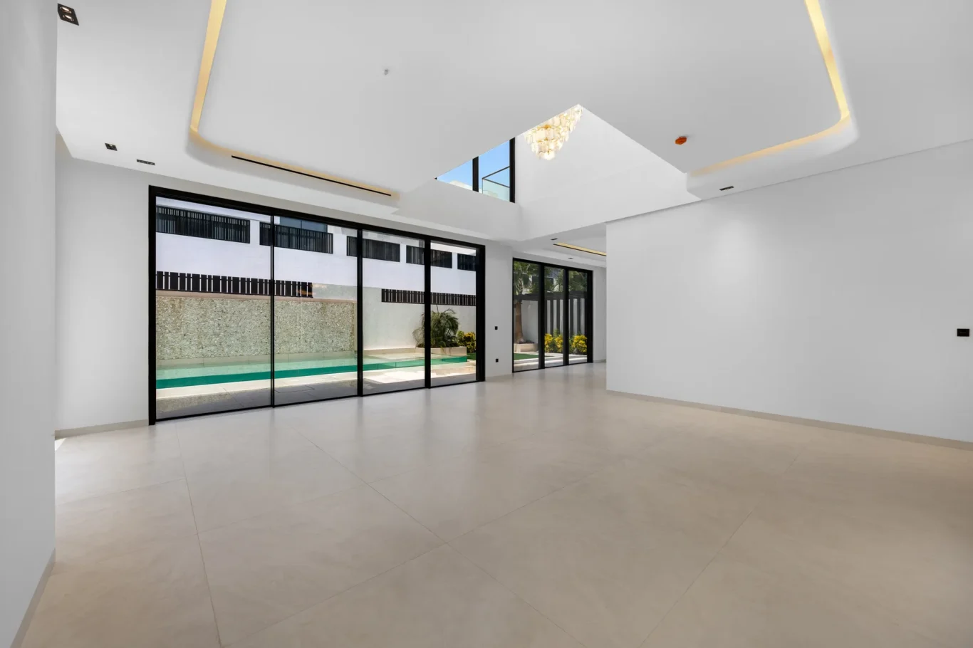 Open-plan living area with sliding doors to the pool, unfurnished five-bedroom villa in Al Furjan, Dubai.