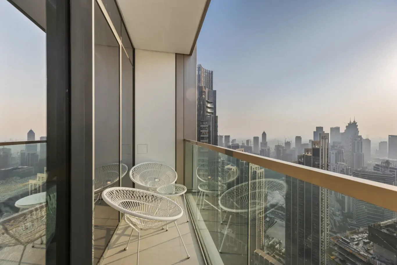 Balcony with glass railing and chairs overlooking the Downtown Dubai skyline. Airbnb photography by MRPS for Solea Stay in Dubai.