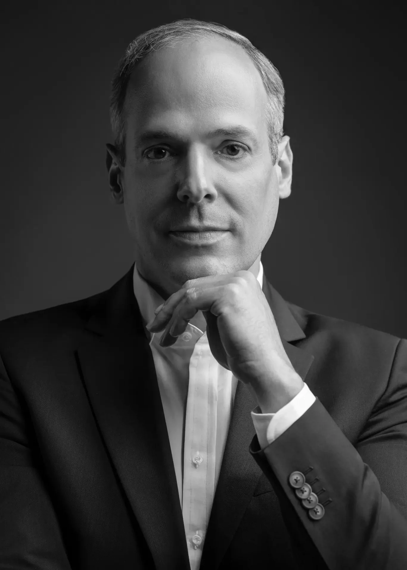Black and white close-up headshot with hand on chin for LinkedIn. Corporate business portrait of a Dubai CEO, photographed at the MRPS studio in Business Bay.
