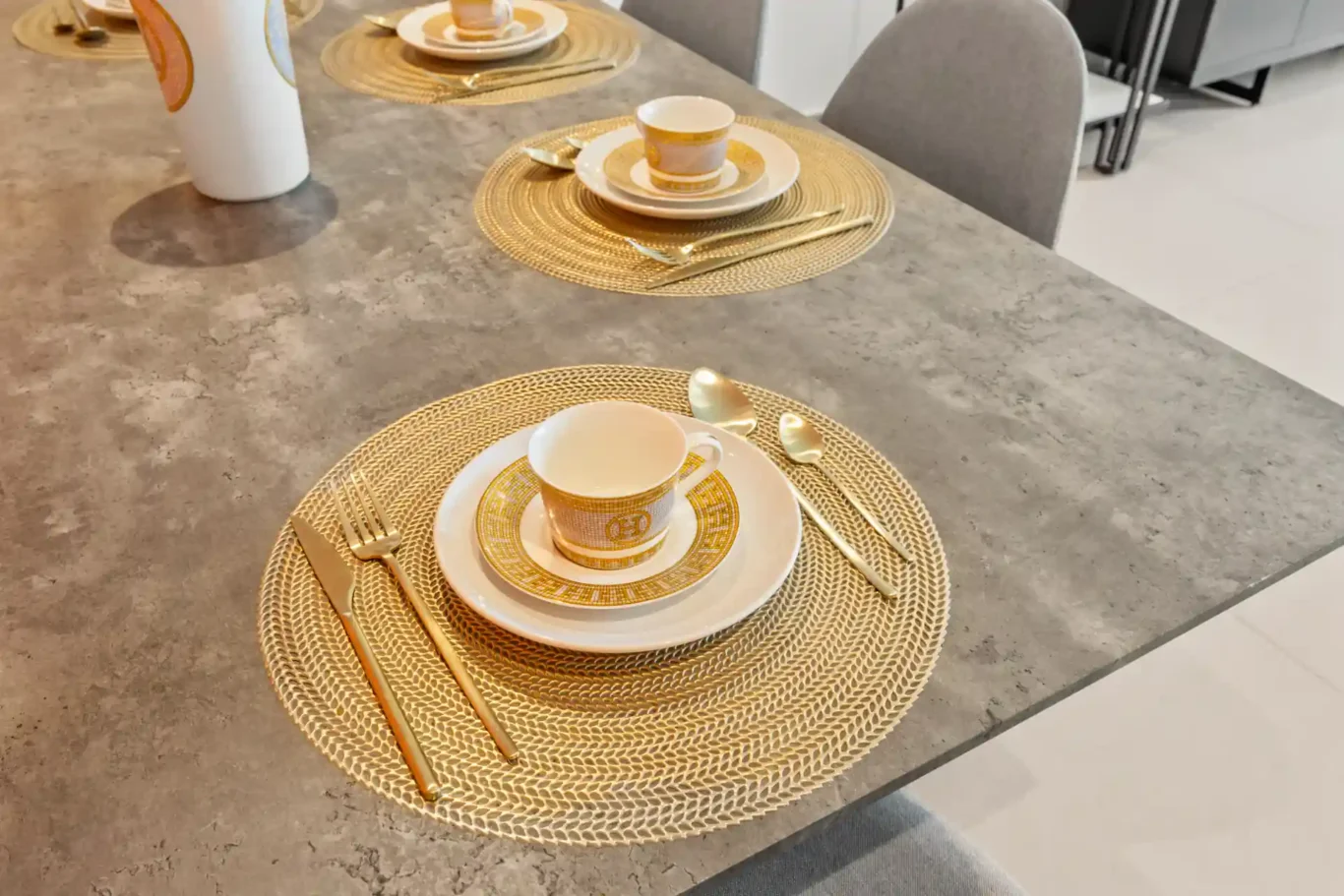 Dining table place setting with round woven mats and gold cutlery. Day, twilight and night Airbnb photography by MRPS for Vista Haus Holiday Homes in Downtown Dubai.