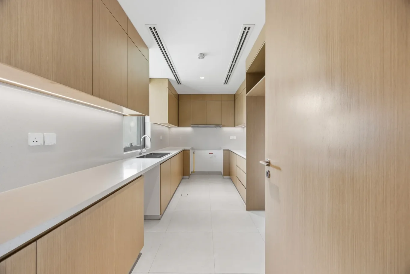 Fitted kitchen with timber cabinets and white counters. Villa photography by MRPS in Dubai for ELITE Property Brokerage.