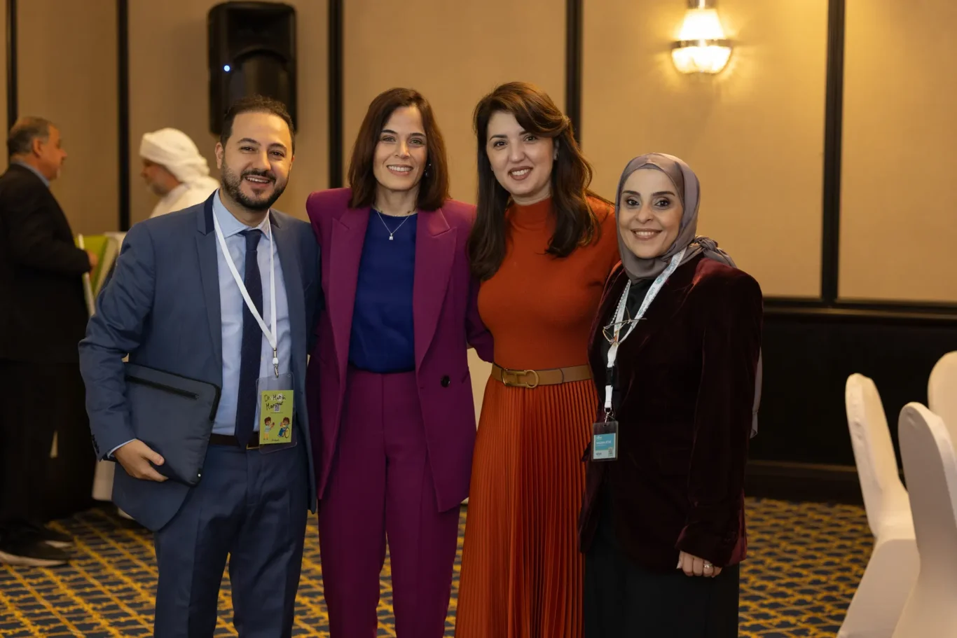 Four members of the organising team posing for a group photo in the ballroom. Corporate event photography by MRPS for My Arabic Publishing at Movenpick Grand Al Bustan, Dubai.