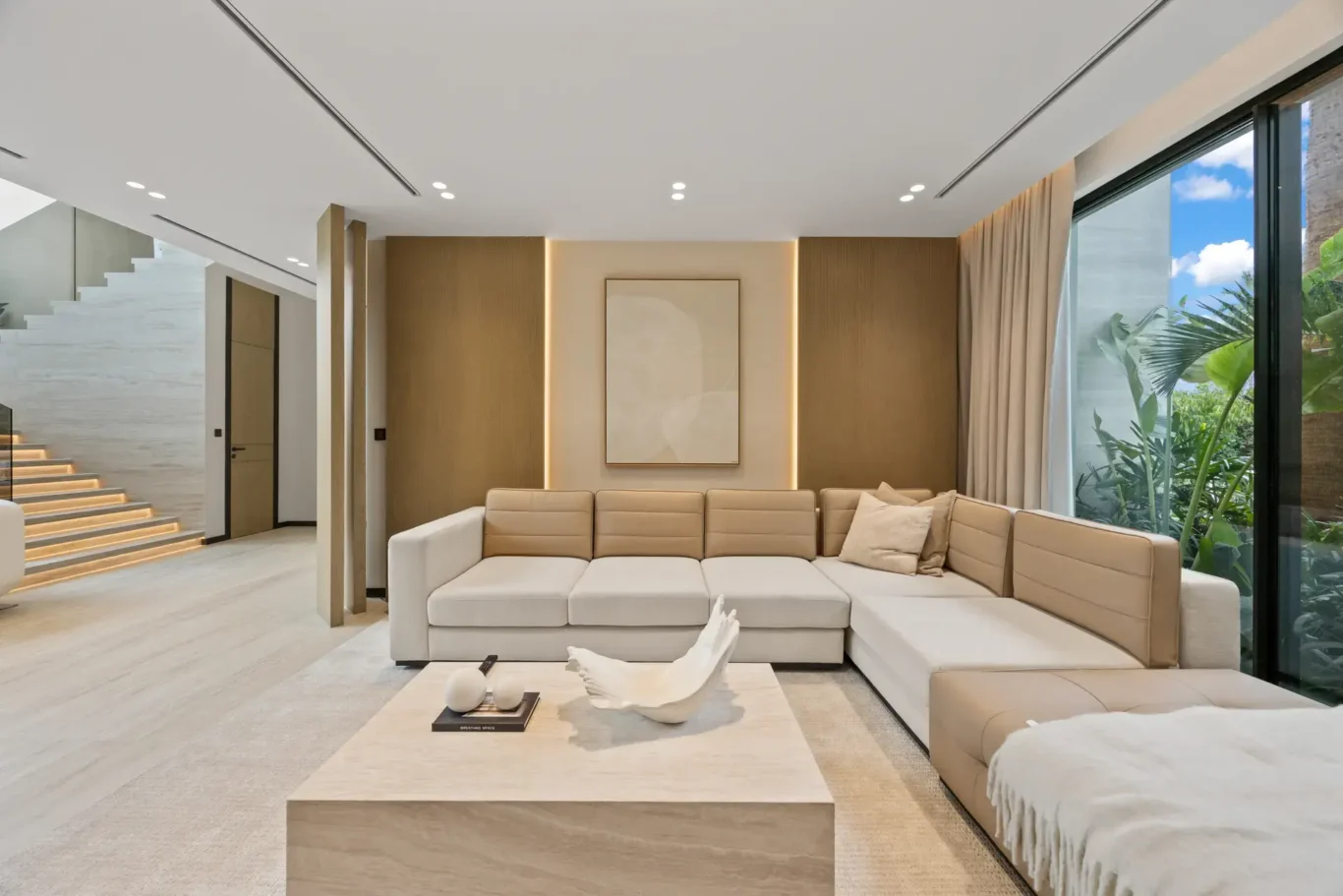 Family lounge with a large sofa, stone coffee table and wood feature wall, luxury villa in Jumeirah Islands, Dubai.