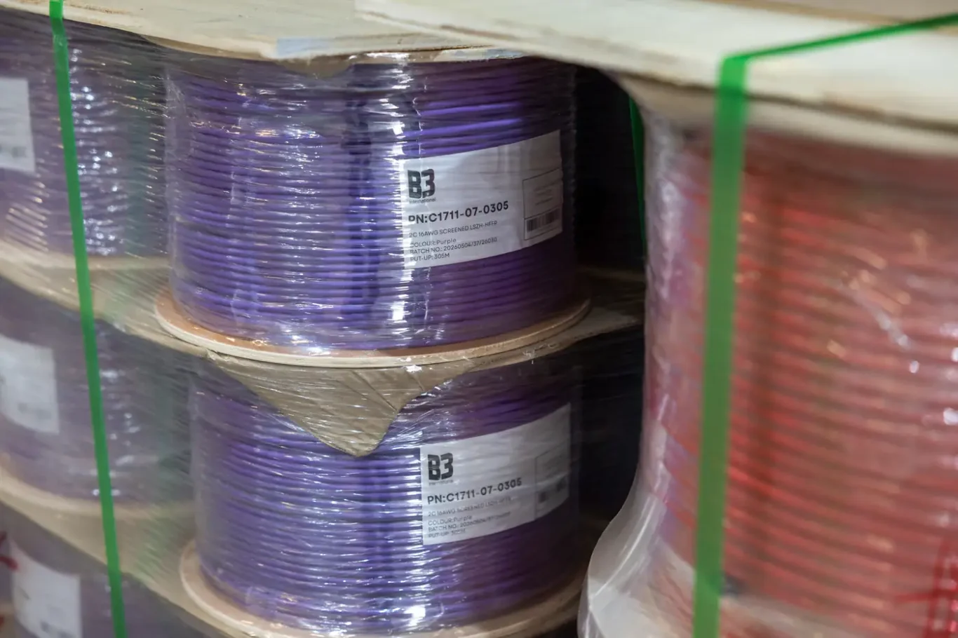 Detail of purple and red cable reels strapped on a pallet at the B3 International warehouse in Dubai.