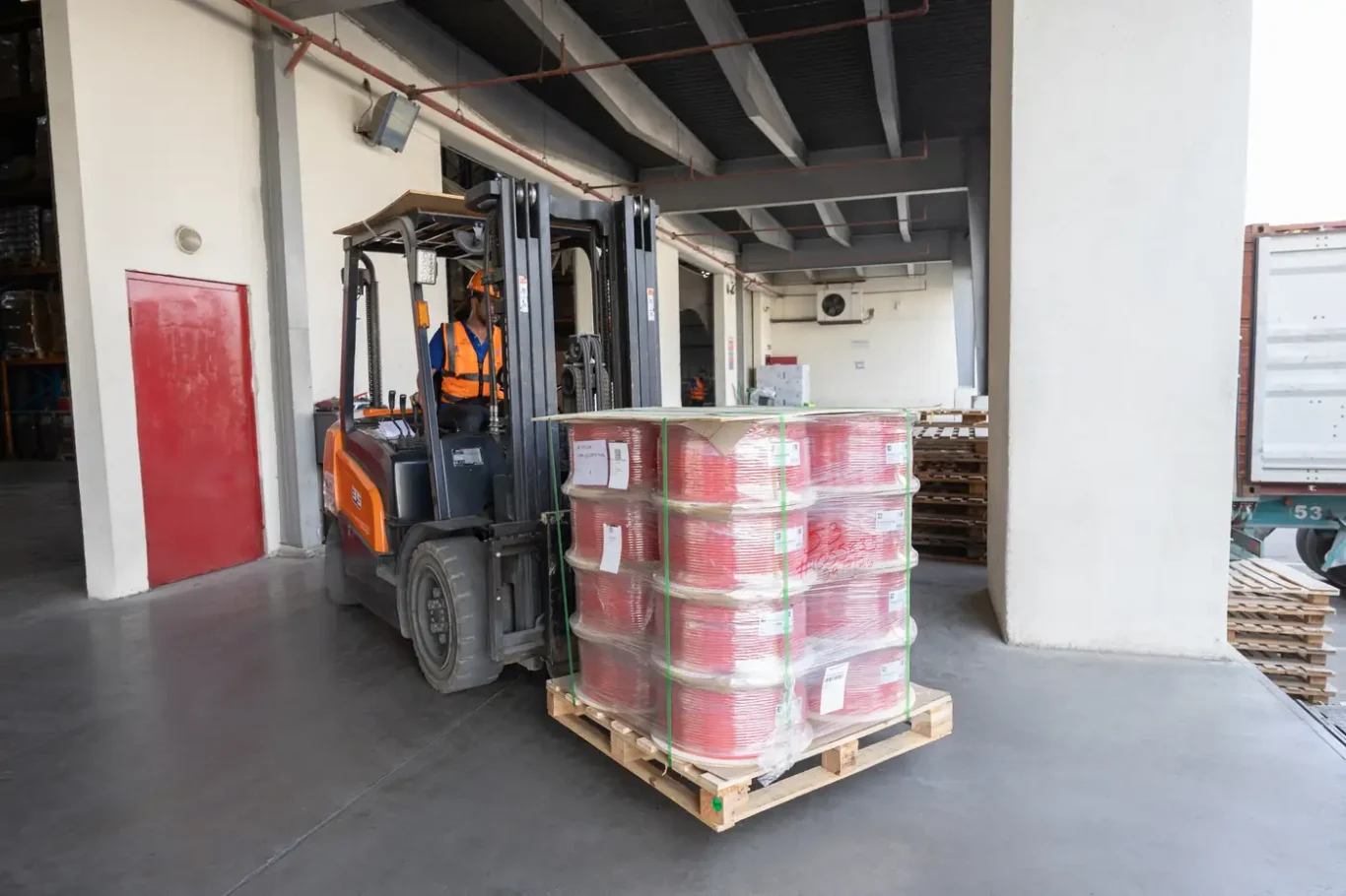Forklift bringing a pallet of red cable reels out to the loading dock at the Jebel Ali warehouse.