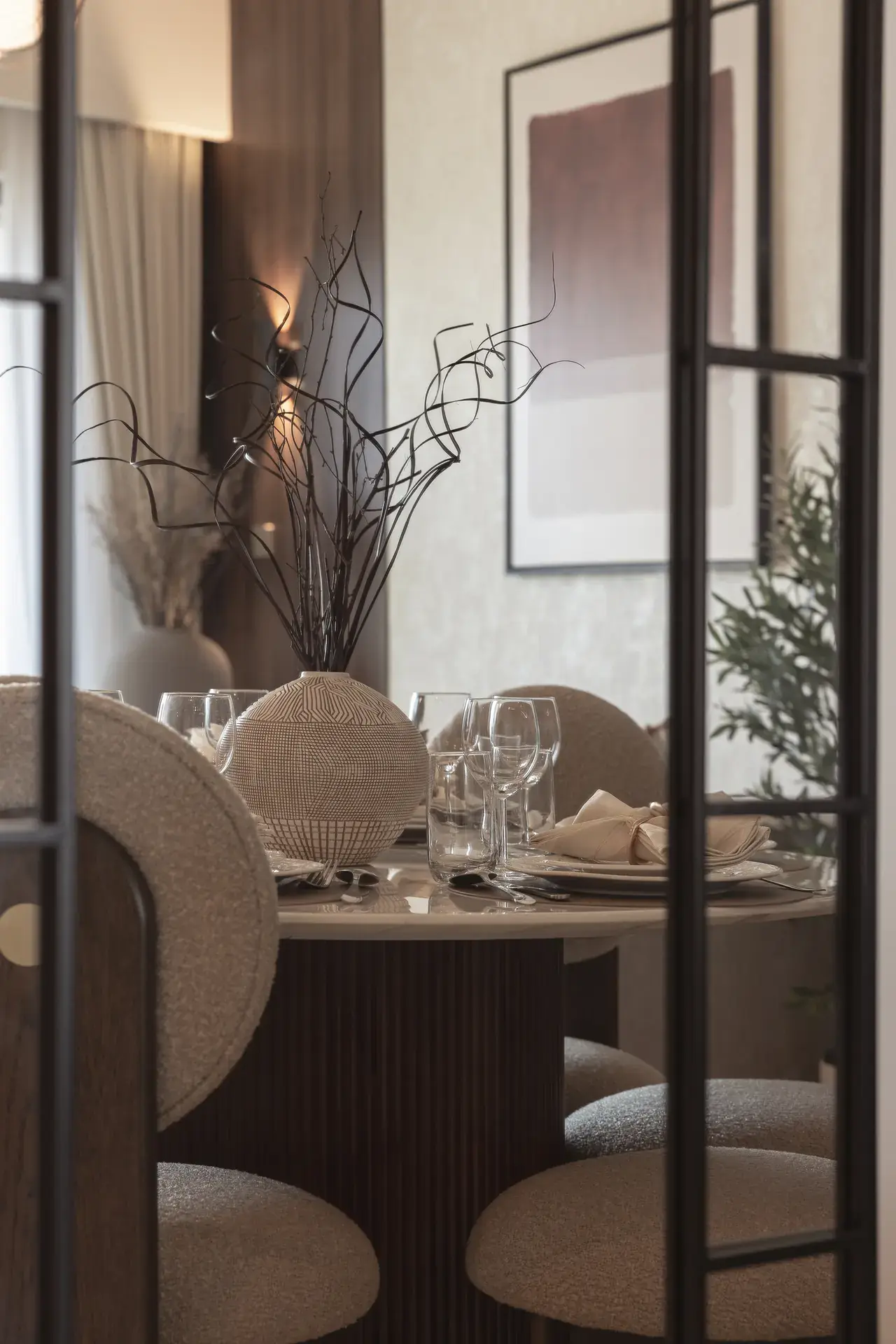 Dining area seen through a black framed glass door. Interior design photography for Aziza Home by MRPS in Dubai.
