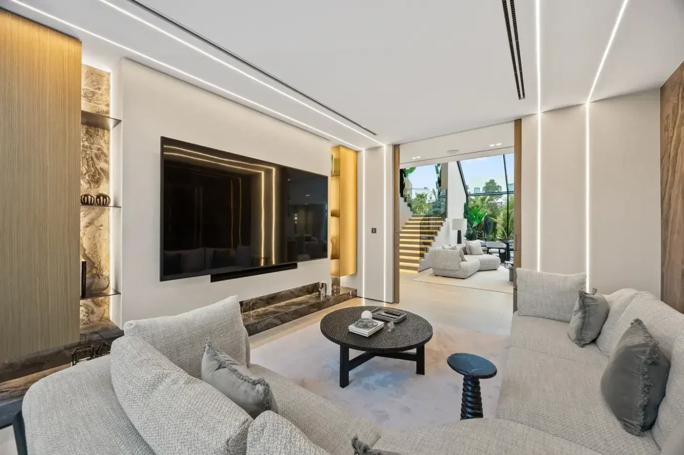 TV lounge with a media wall and round coffee table, luxury villa in Jumeirah Islands, Dubai.