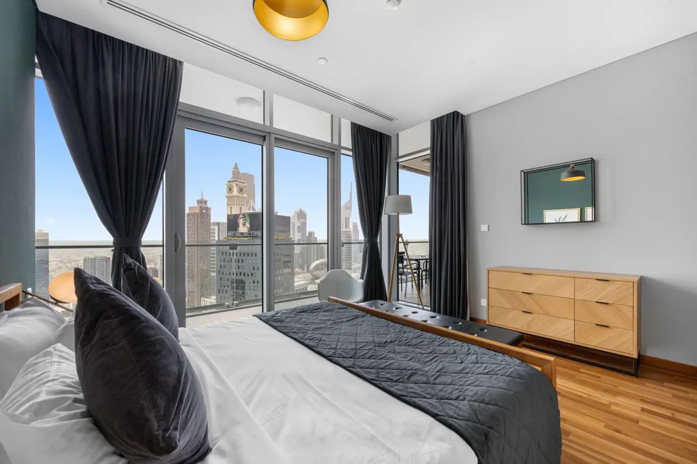 Bedroom with the DIFC skyline through the windows in a Your Stay Apartments one-bedroom at Burj Daman, DIFC, Dubai.