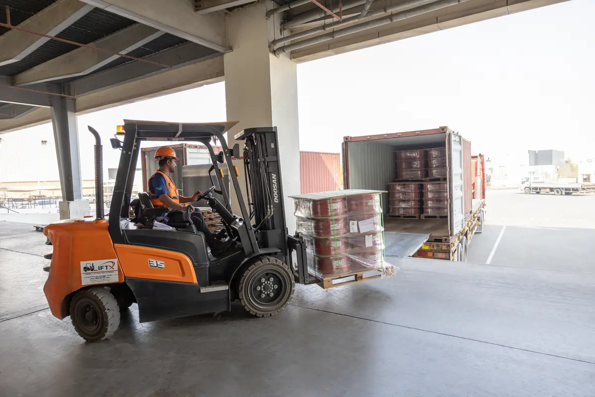 Forklift loading a pallet of B3 International cable reels into a shipping container at the Jebel Ali warehouse.