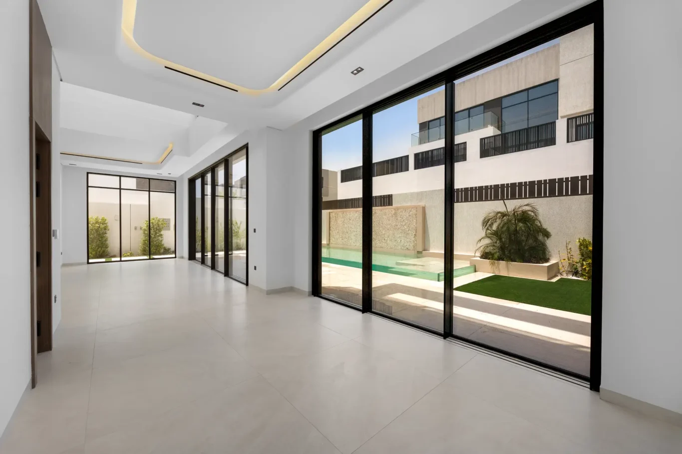 Living room with full-height sliding doors to the pool and garden, unfurnished five-bedroom villa in Al Furjan, Dubai.
