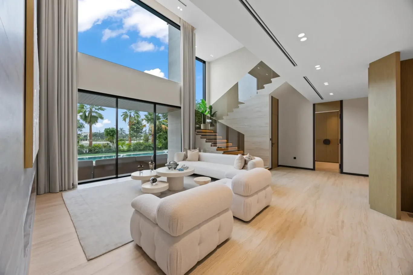 Living room with boucle armchairs and floor-to-ceiling windows, luxury villa in Jumeirah Islands, Dubai.