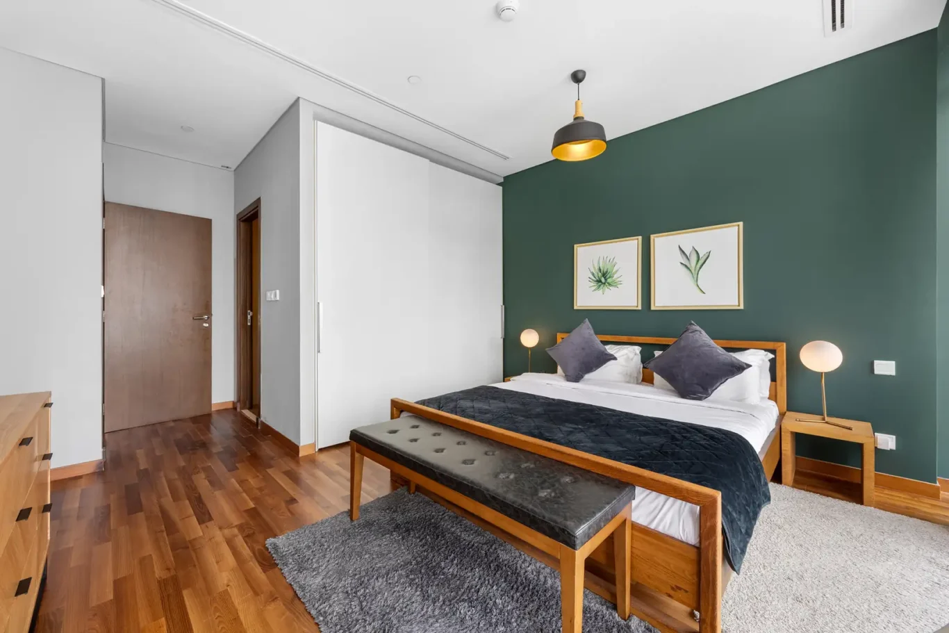 Bedroom with built-in wardrobe and bench in a Your Stay Apartments one-bedroom at Burj Daman, DIFC, Dubai.