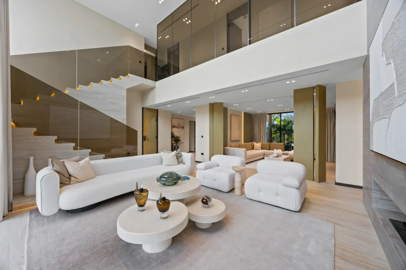 Living room with a curved sofa and round coffee tables under the glass mezzanine, luxury villa in Jumeirah Islands, Dubai.