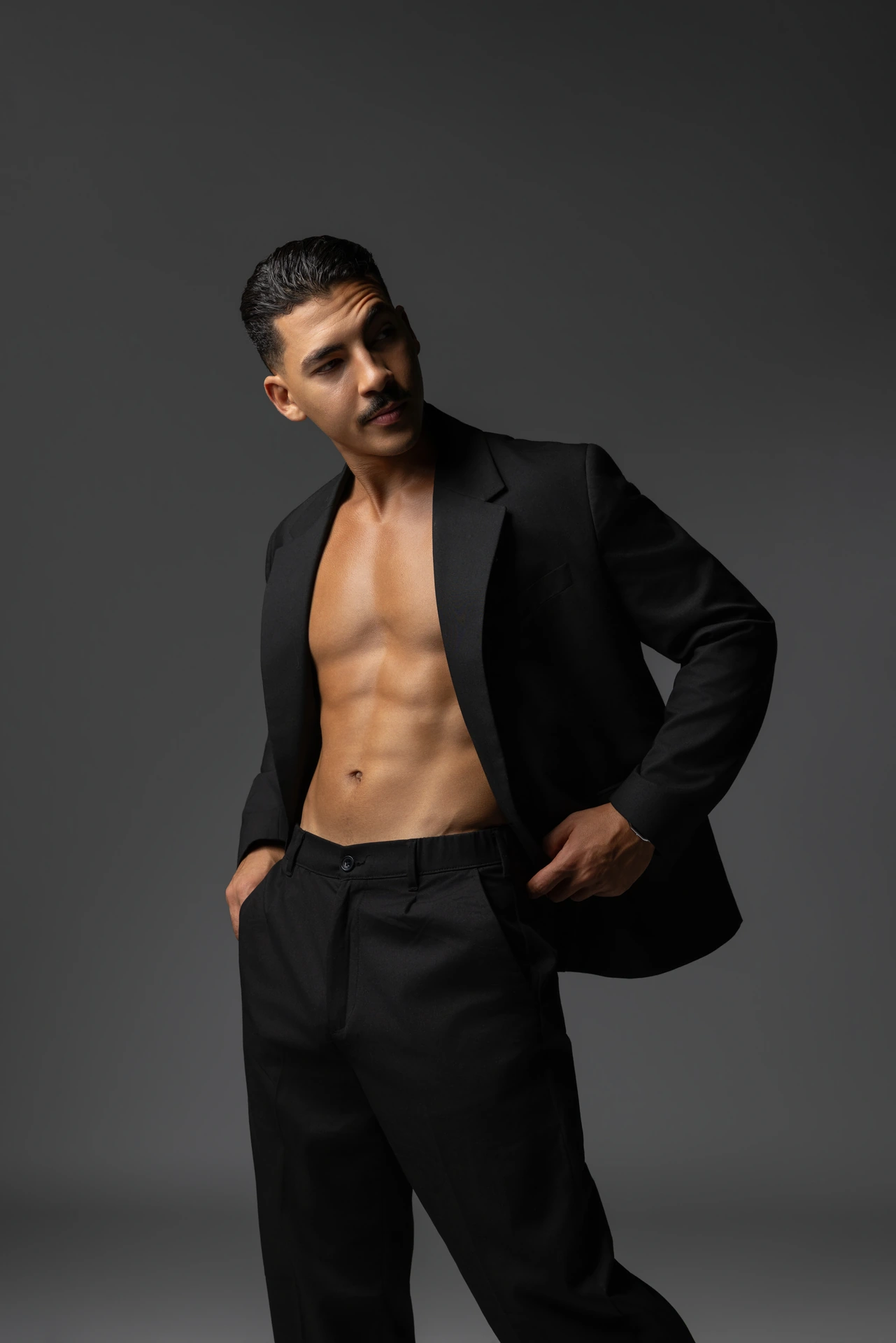 Standing in an open black blazer with a hand in the trouser pocket. Male modeling portfolio photoshoot by MRPS in Dubai, photographed by Nastaran.