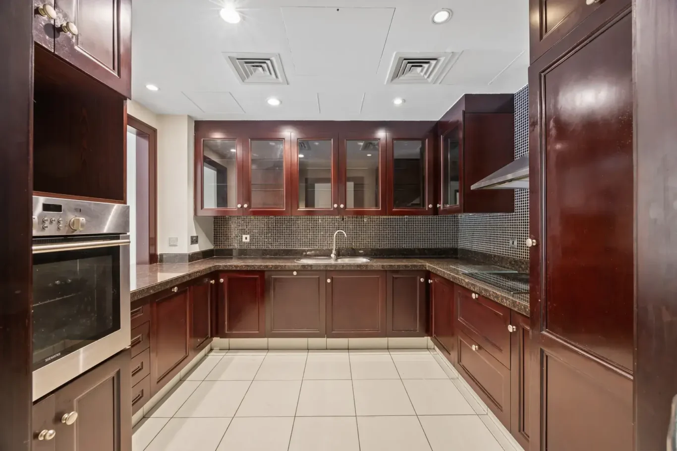 Fitted kitchen with dark wood cabinets and granite worktops in an unfurnished two-bedroom garden apartment in Old Town, Downtown Dubai, photographed for ELITE Property Brokerage.