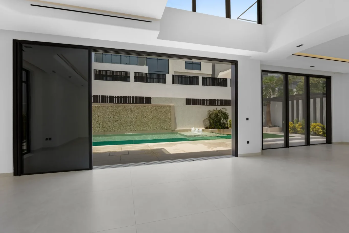 Living room with the sliding doors open to the pool terrace, unfurnished five-bedroom villa in Al Furjan, Dubai.