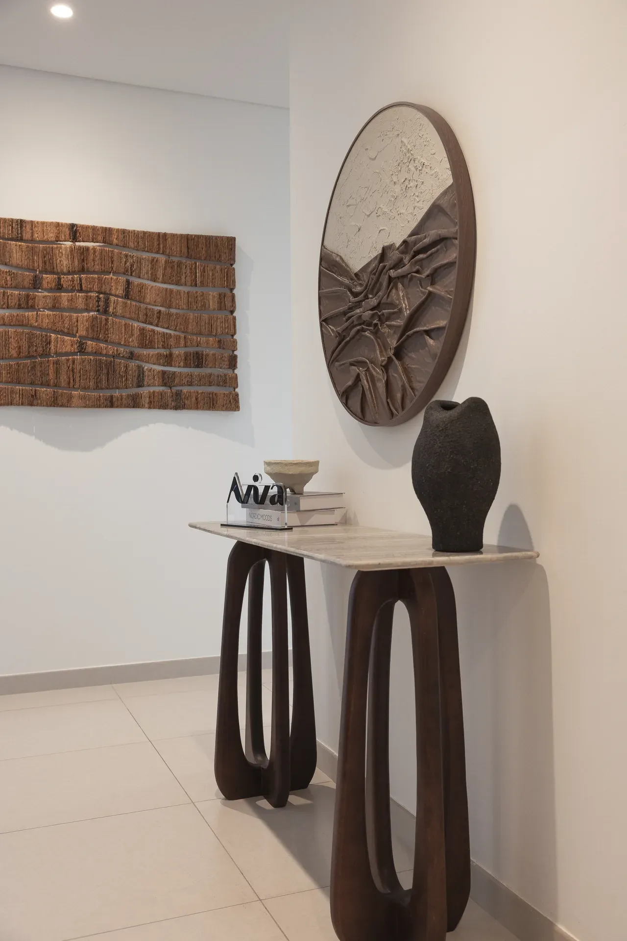 Entrance with walnut console table, round wall art and wooden wall decor. Interior design photography for Aziza Home by MRPS in Dubai.