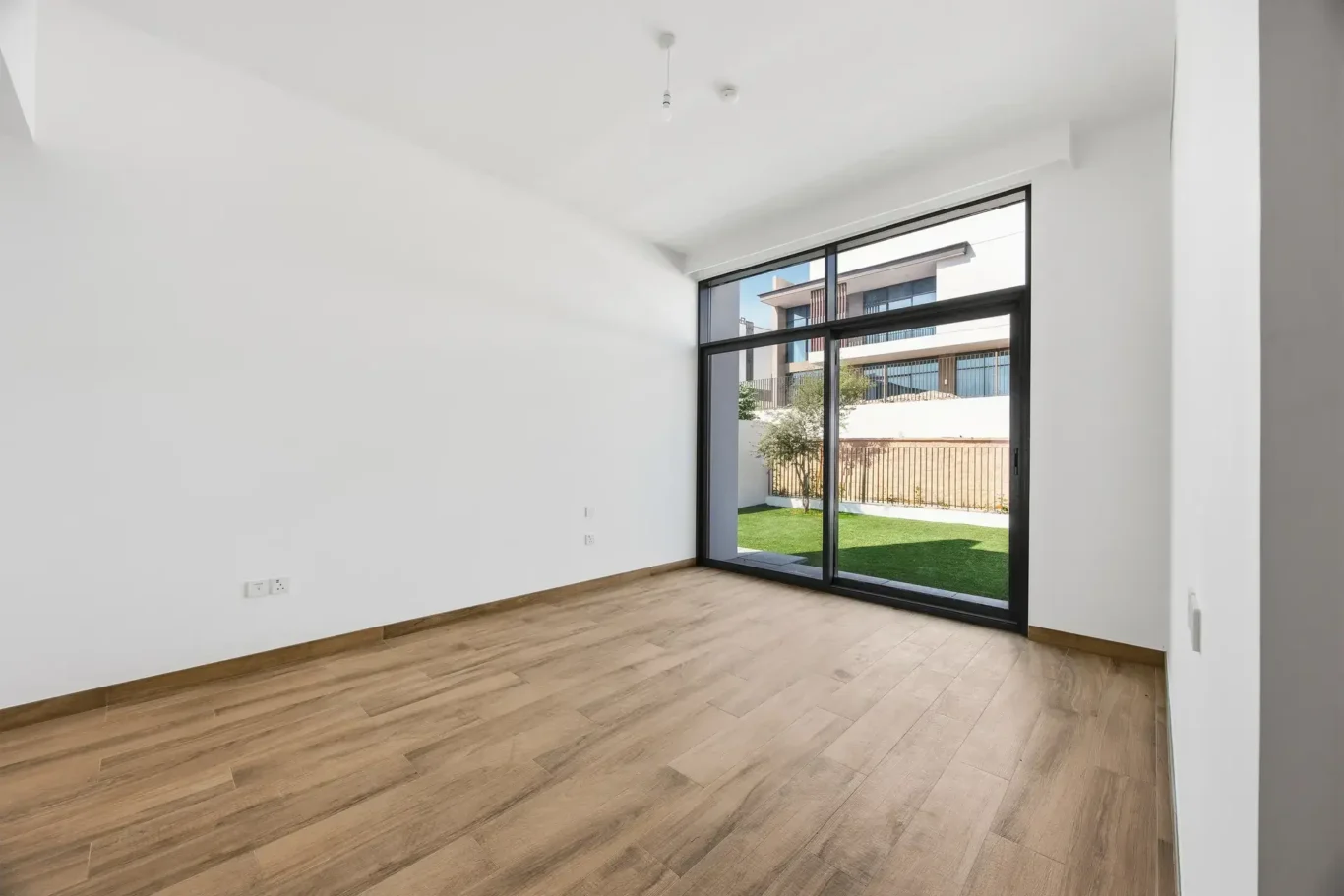 Ground floor bedroom with wood flooring and doors to the garden. Villa photography by MRPS in Dubai for ELITE Property Brokerage.