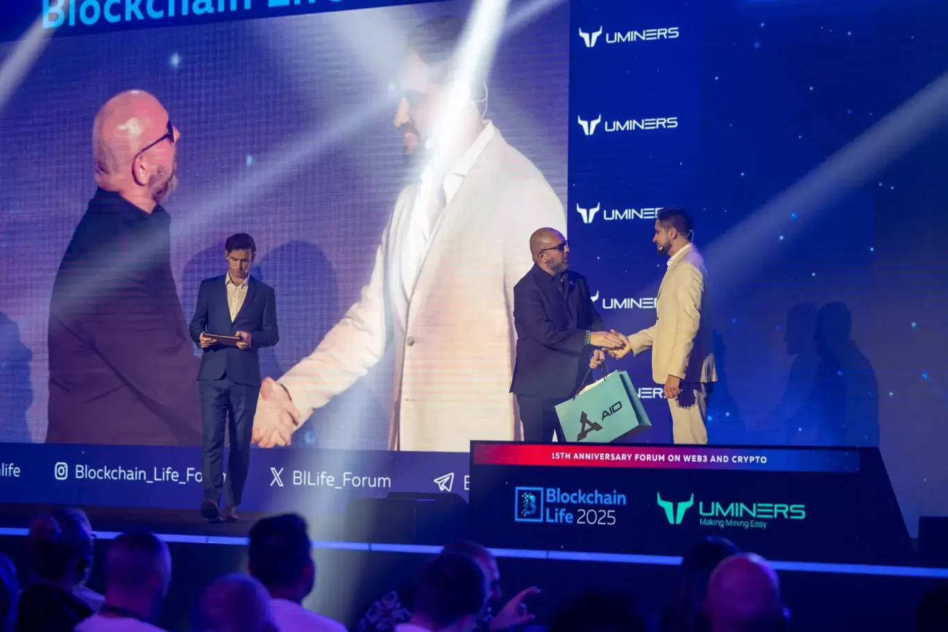 Handshake on stage during an award presentation. Event photography by MRPS at Blockchain Life 2025, Festival Arena, Dubai.