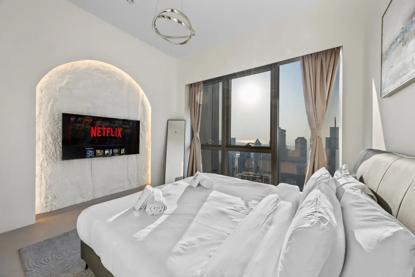Master bedroom with arched backlit TV wall and floor to ceiling windows. Airbnb photography by MRPS for Solea Stay in Dubai.