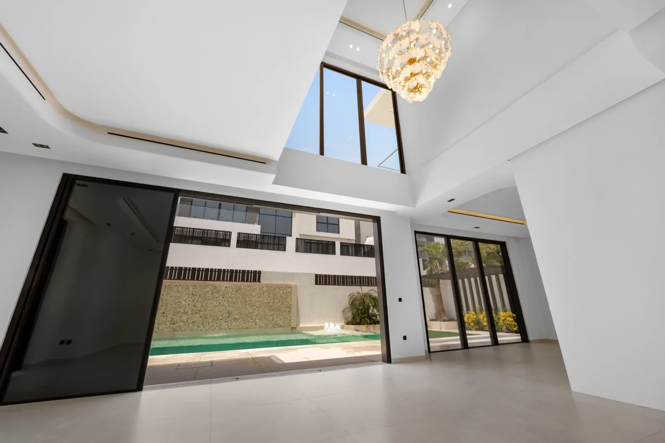 Double-height living room with a crystal chandelier, unfurnished five-bedroom villa in Al Furjan, Dubai.