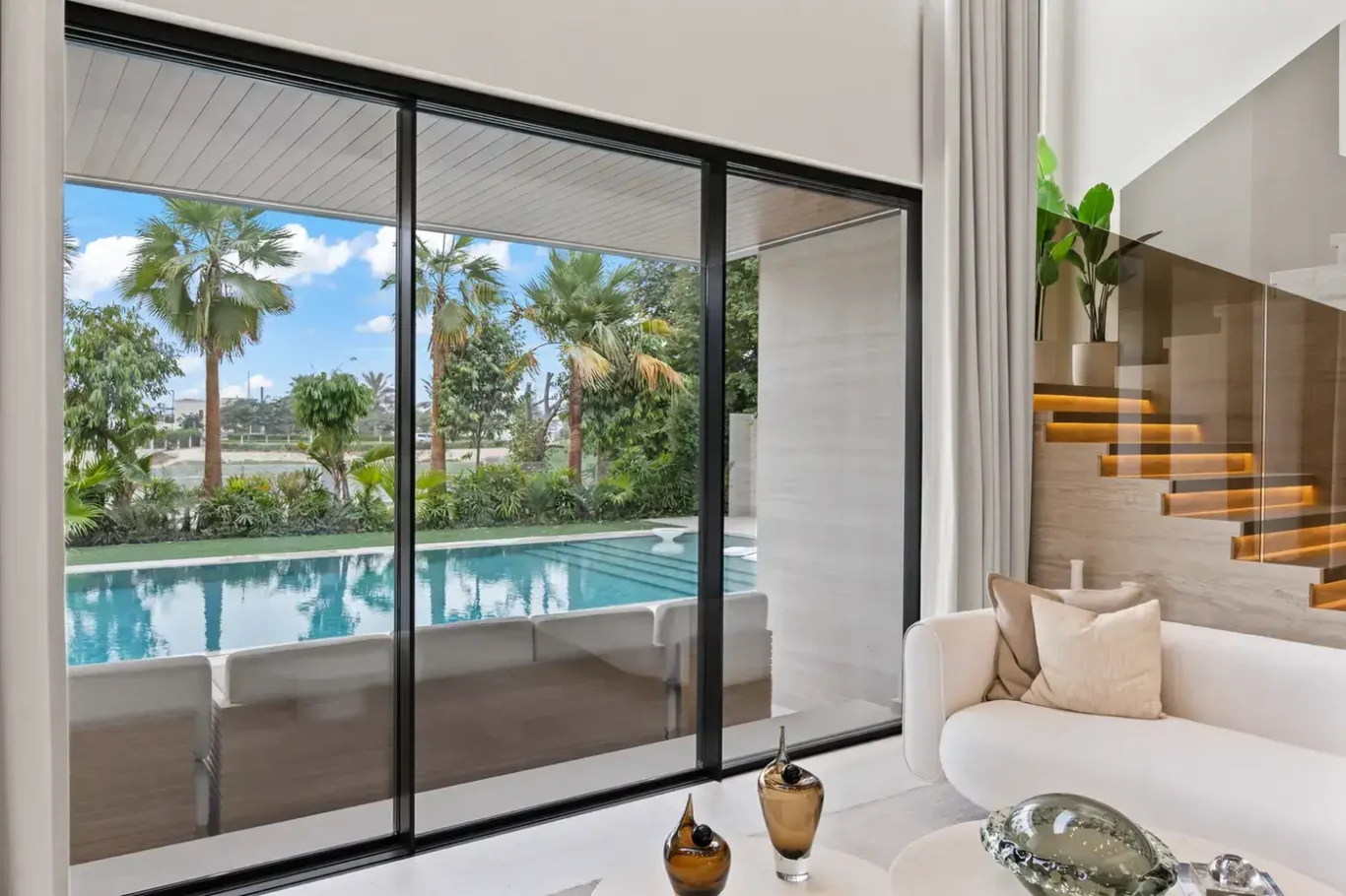 Living room sliding doors opening onto the swimming pool and palm garden, luxury villa in Jumeirah Islands, Dubai.