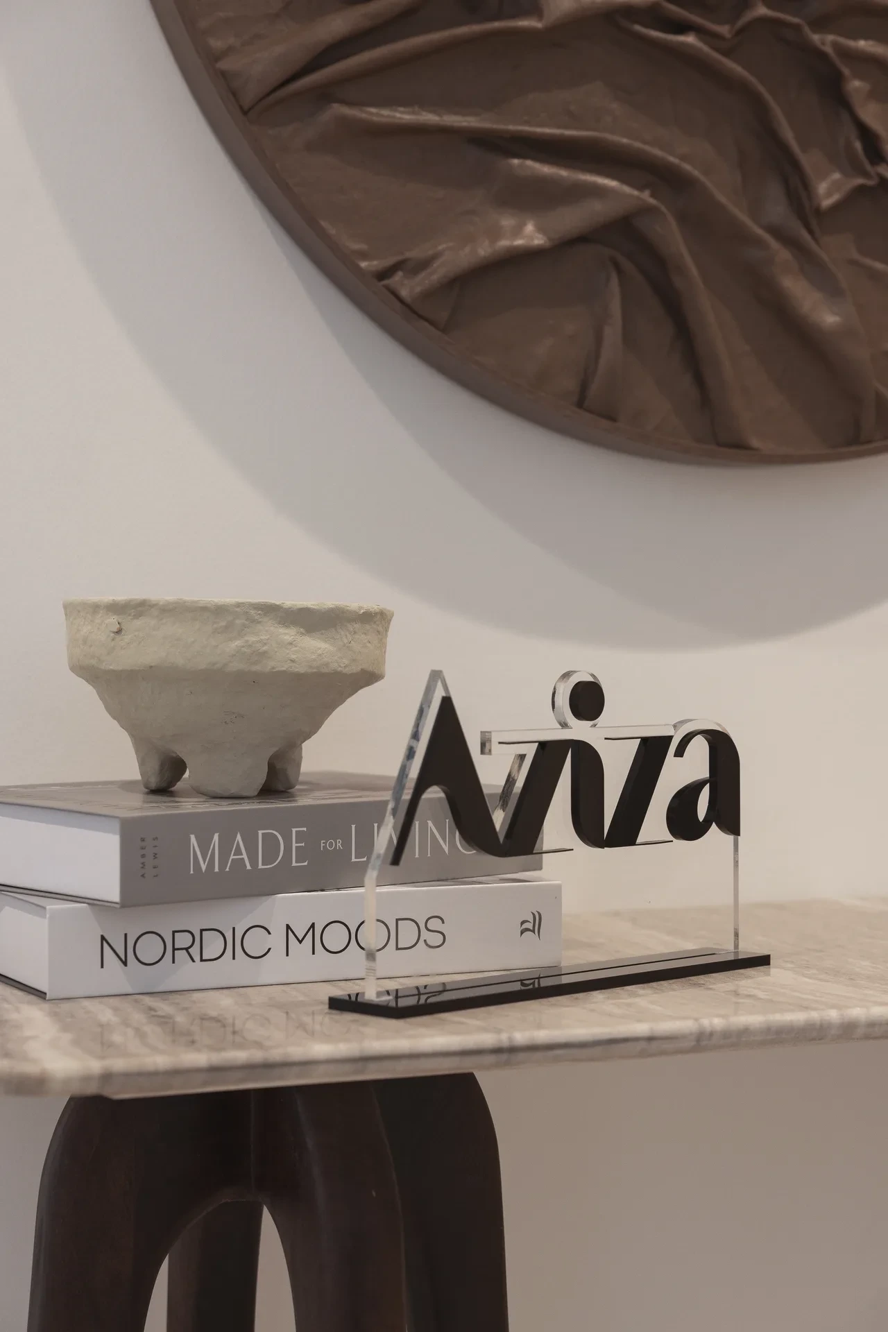 Console styling with coffee table books and an Aziza sign. Interior design photography for Aziza Home by MRPS in Dubai.