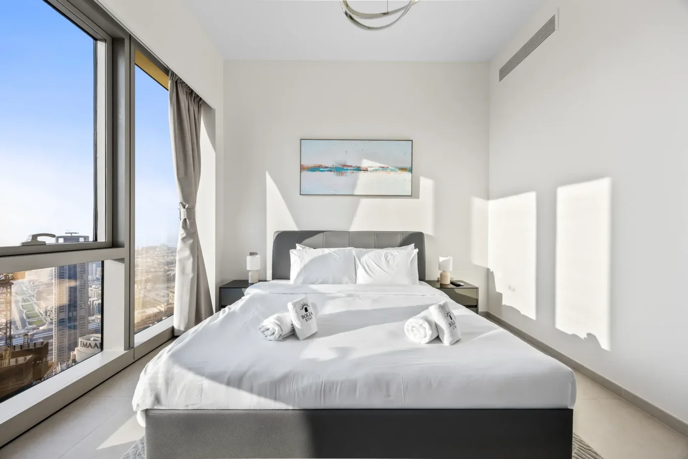 Master bed beside large windows with skyline views. Airbnb photography by MRPS for Solea Stay in Dubai.