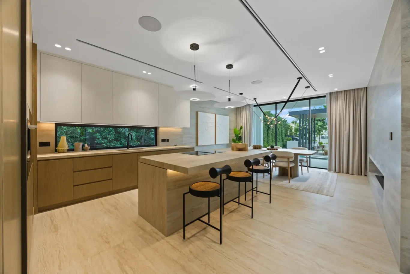 Open kitchen with a stone island, bar stools and wood cabinetry, luxury villa in Jumeirah Islands, Dubai.