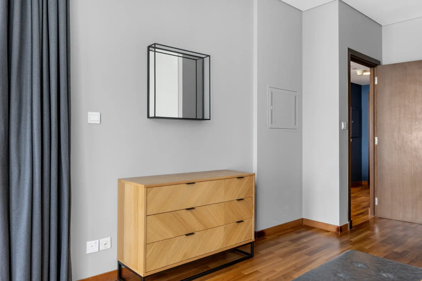 Wood dresser and mirror in the bedroom in a Your Stay Apartments one-bedroom at Burj Daman, DIFC, Dubai.