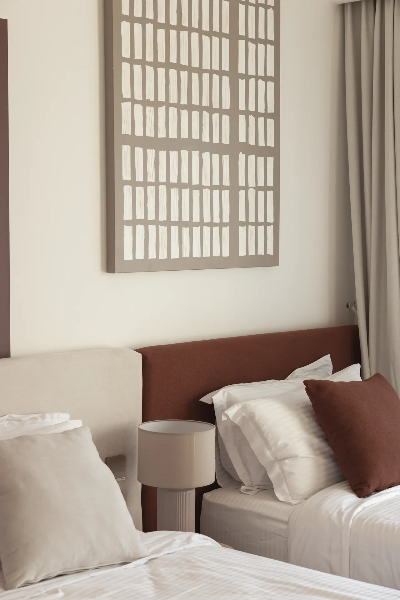 Bedroom with rust headboard, white bedding and patterned wall art. Interior design photography for Aziza Home by MRPS in Dubai.