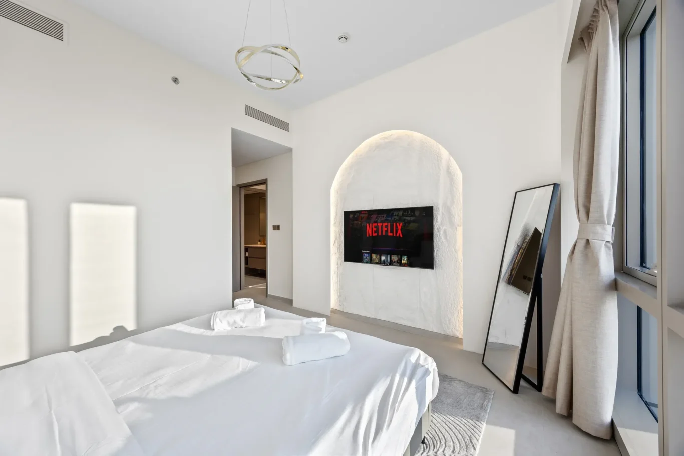 Master bedroom seen from the door with the arched TV wall. Airbnb photography by MRPS for Solea Stay in Dubai.