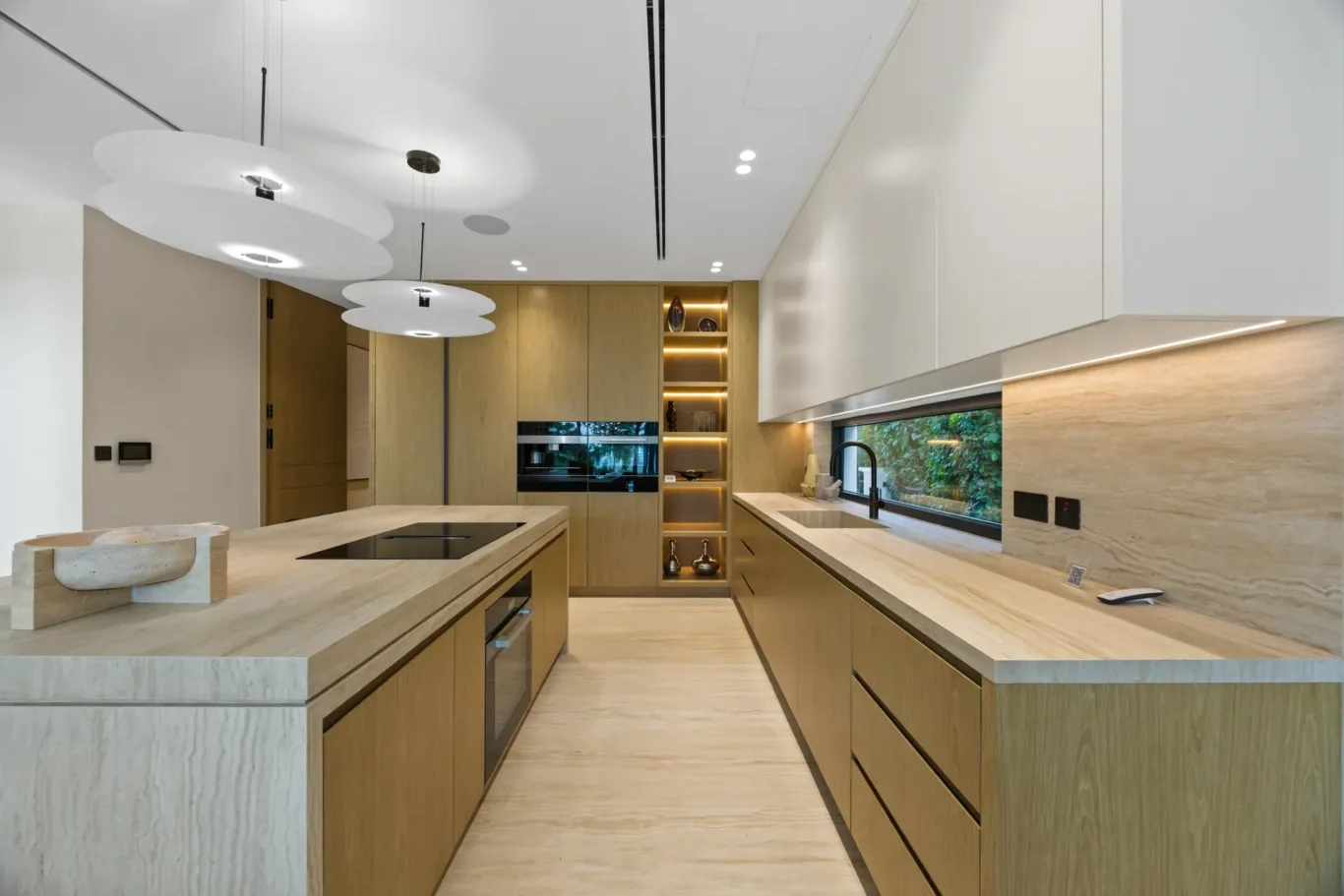 Kitchen island with an induction hob under round pendant lights, luxury villa in Jumeirah Islands, Dubai.