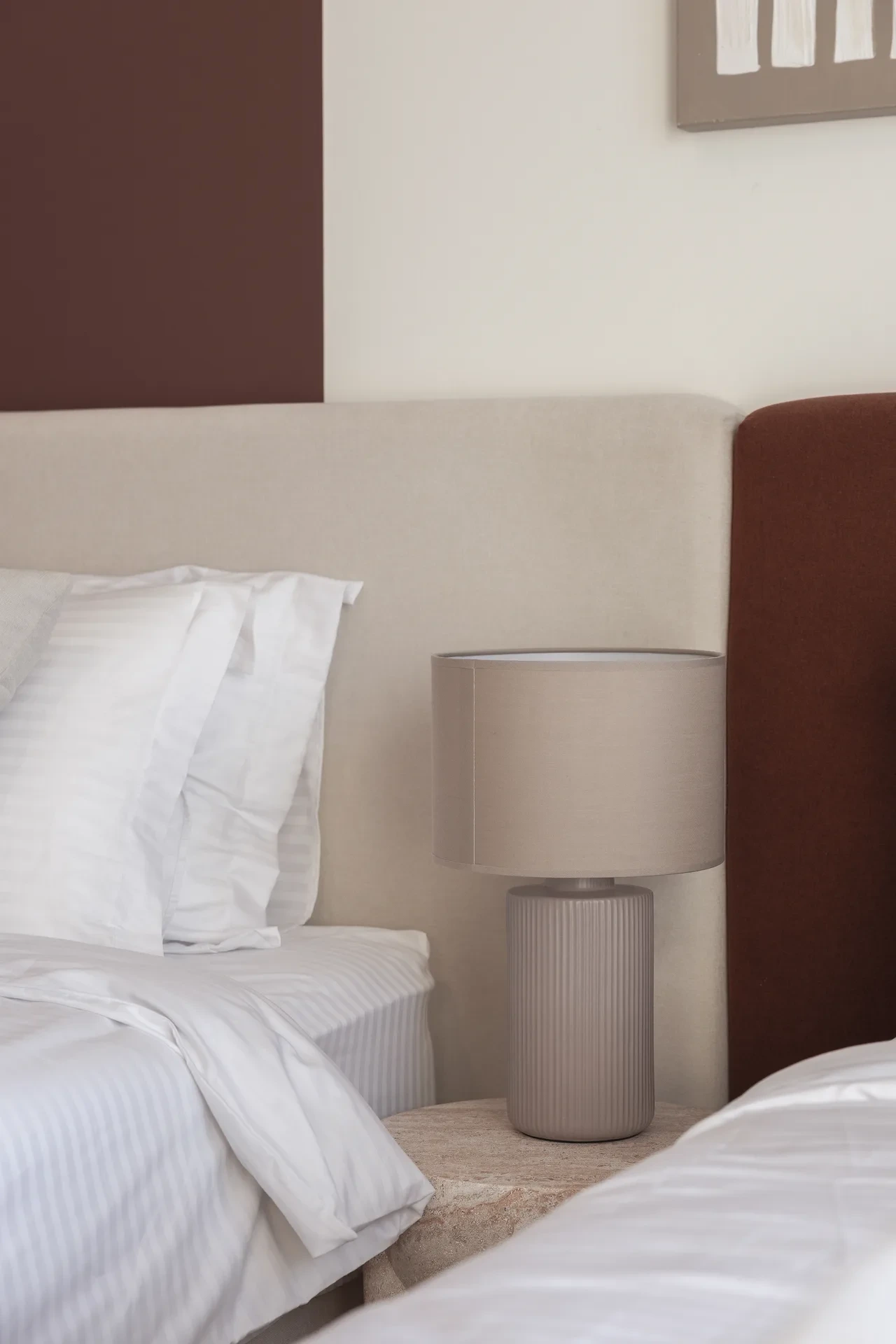 Bedside table with a ceramic lamp next to the upholstered headboard. Interior design photography for Aziza Home by MRPS in Dubai.
