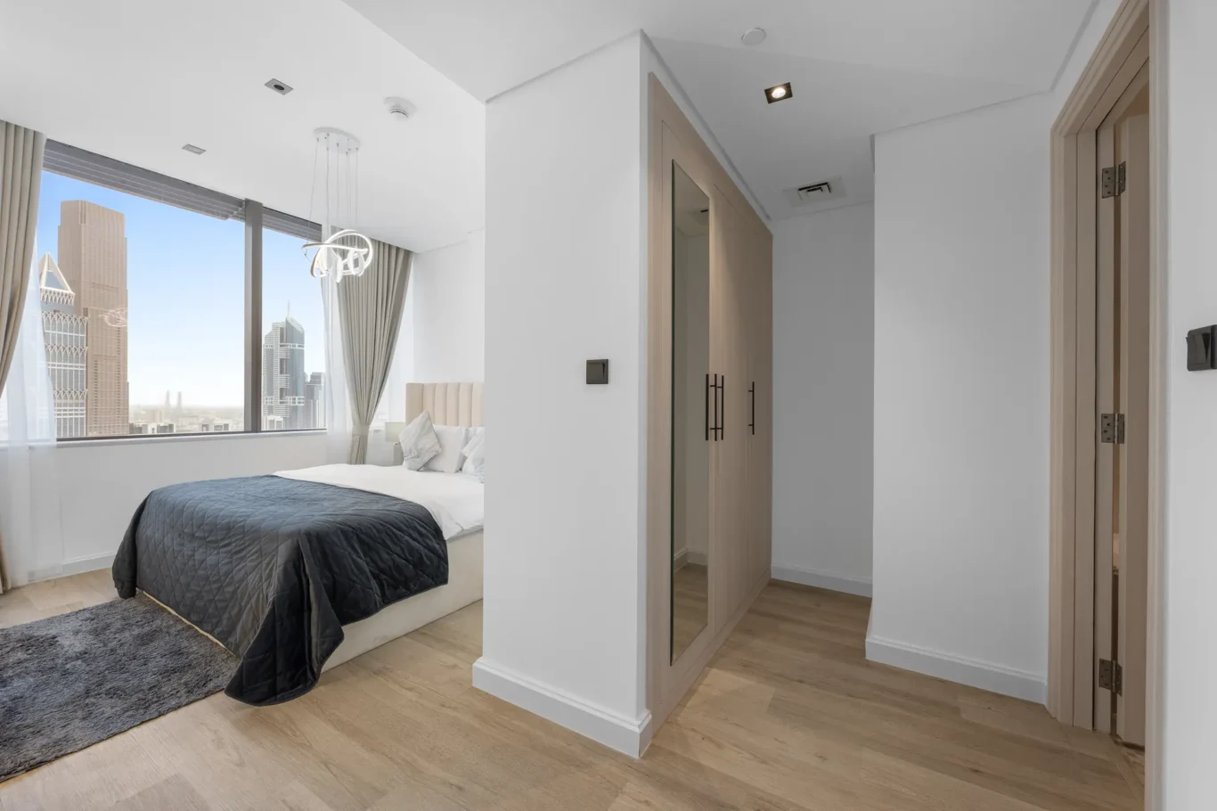 Bedroom with wardrobe and bathroom door in a Your Stay Apartments one-bedroom at Sky Gardens, DIFC, Dubai.