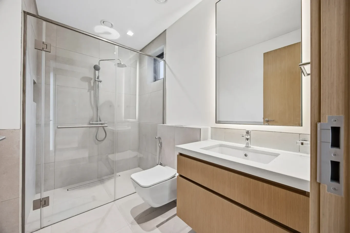 Ground floor bathroom with glass shower and timber vanity. Villa photography by MRPS in Dubai for ELITE Property Brokerage.