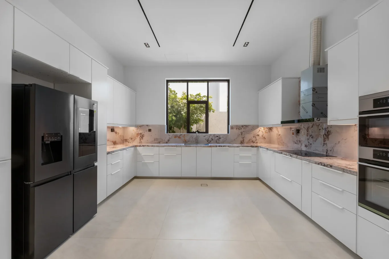 Fitted kitchen with white cabinets and built-in ovens, unfurnished five-bedroom villa in Al Furjan, Dubai.