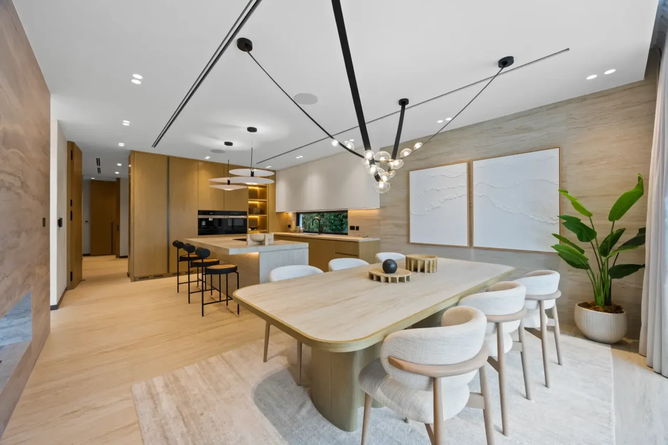 Dining table with the open kitchen and bar stools behind, luxury villa in Jumeirah Islands, Dubai.