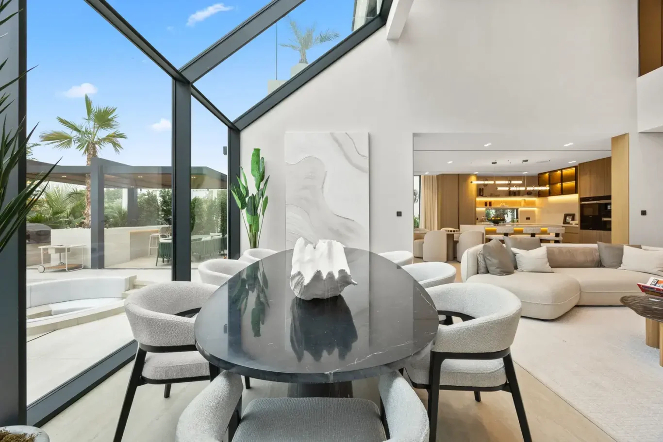 Dining area by the glass wall looking back to the living room, luxury villa in Jumeirah Islands, Dubai.