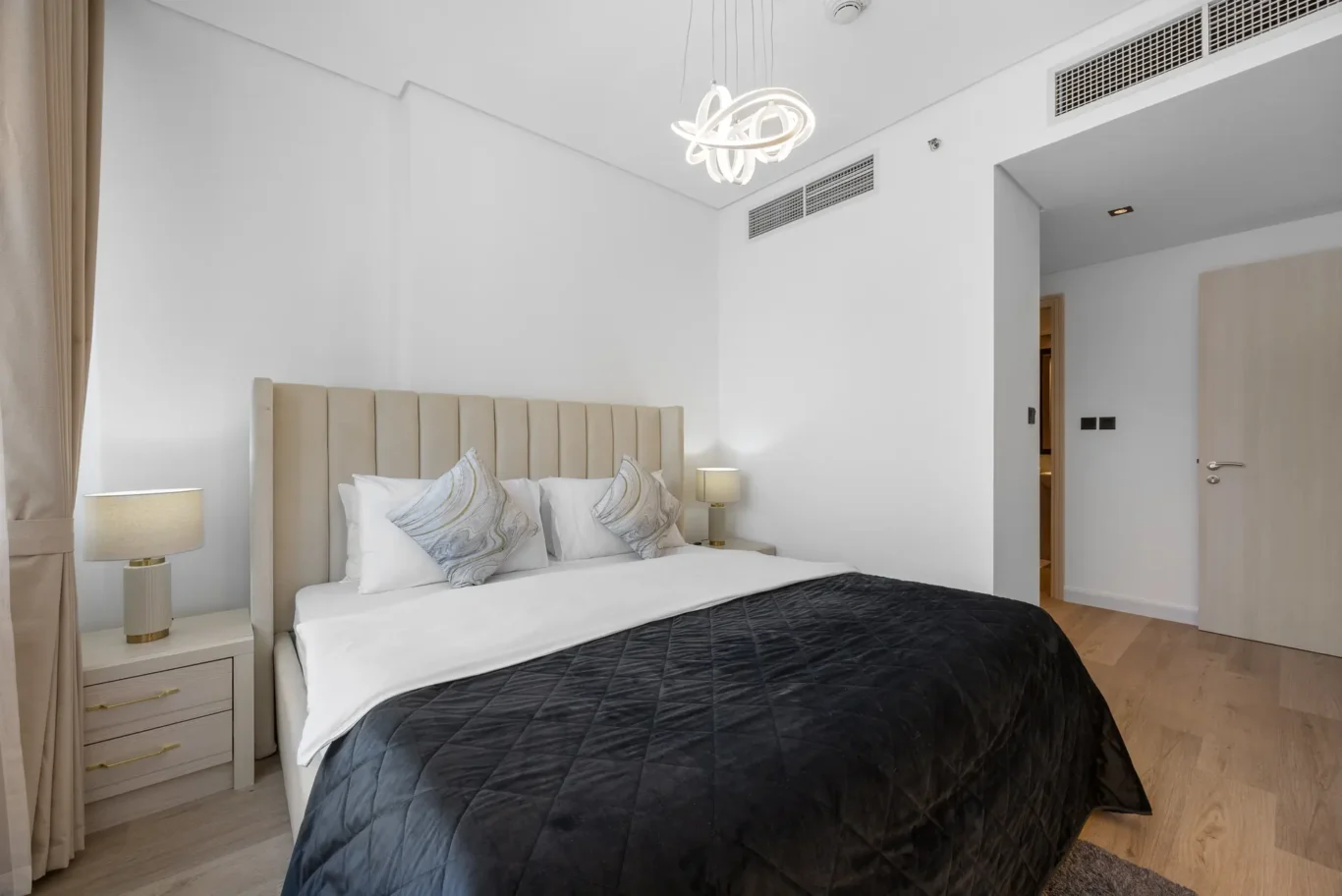 Bed with upholstered headboard and bedside lamps in a Your Stay Apartments one-bedroom at Sky Gardens, DIFC, Dubai.